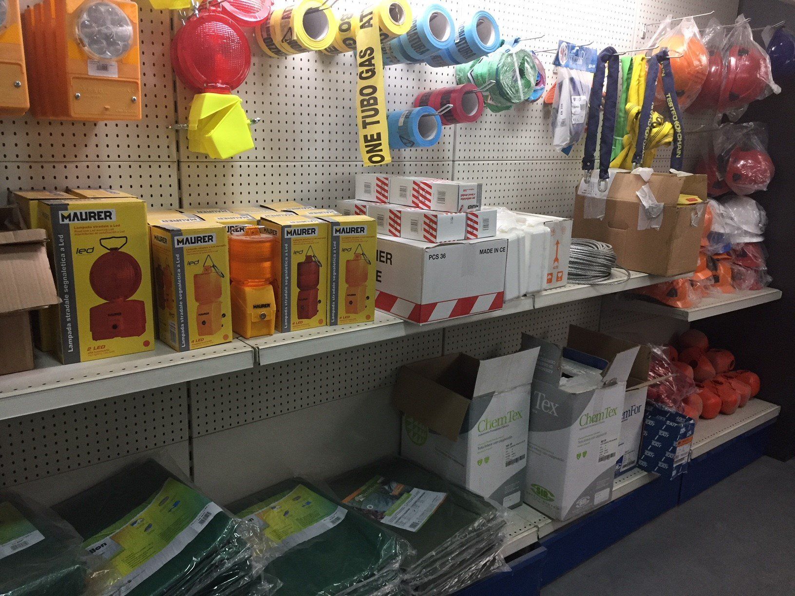 Scaffali di un negozio pieni di attrezzature di sicurezza per l'edilizia, tra cui luci, nastro adesivo e coni.