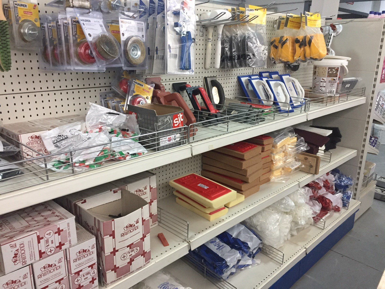 Scaffali di un negozio di ferramenta pieni di vari utensili, forniture e articoli confezionati.