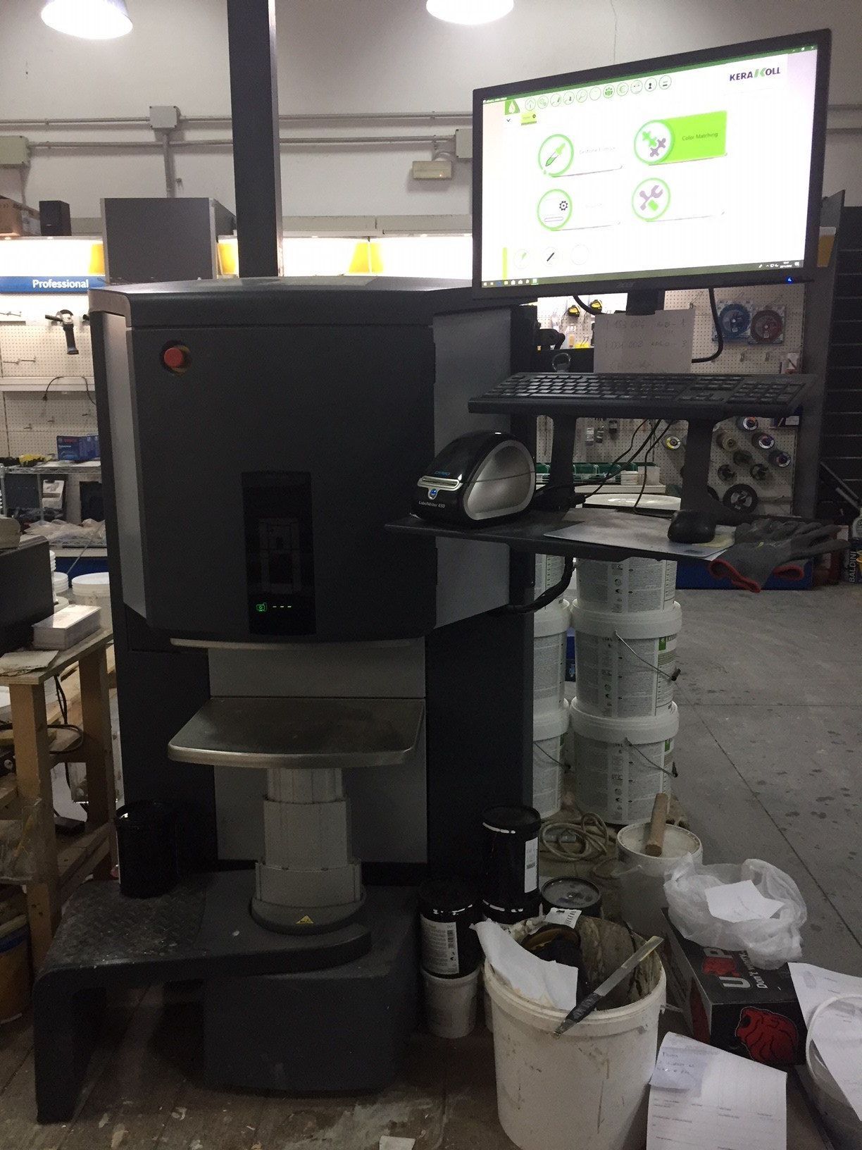 Grande macchina industriale grigio scuro con monitor, tastiera e mouse in un ambiente da officina.