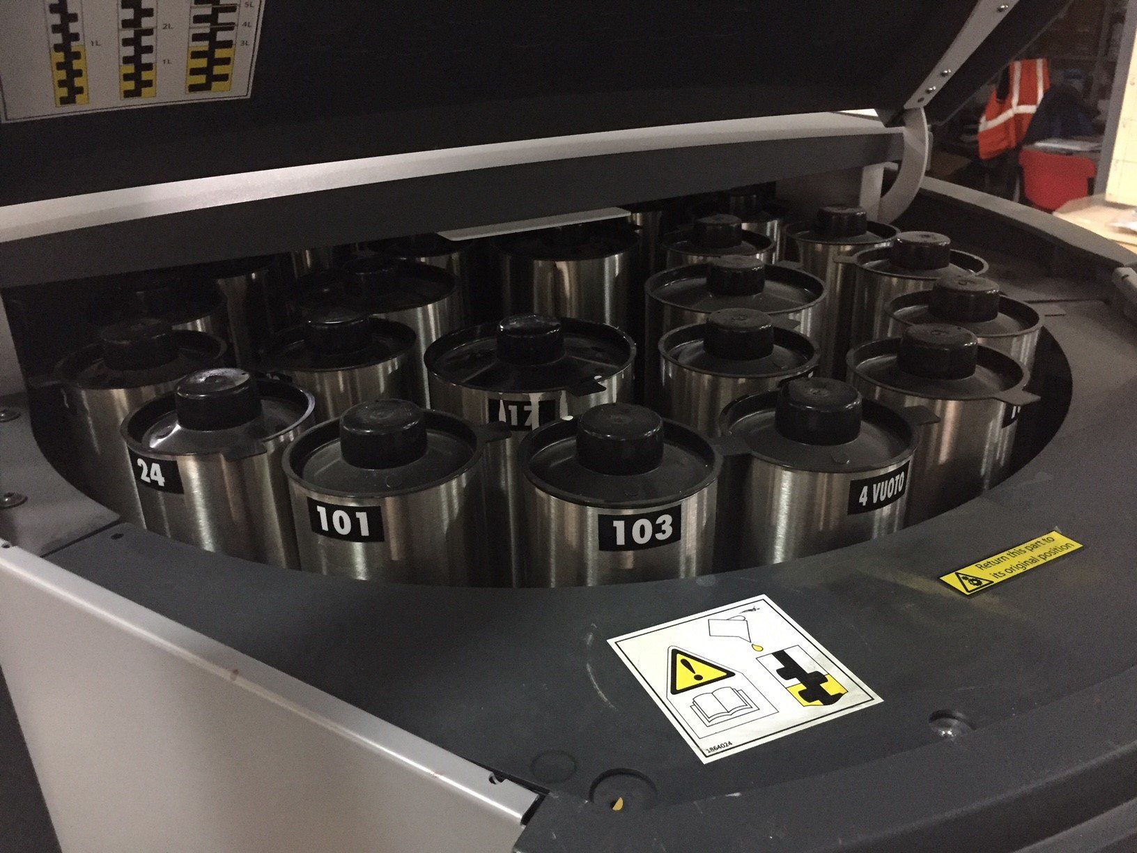 Una macchina con molti contenitori metallici etichettati con numeri, alcuni parzialmente aperti.