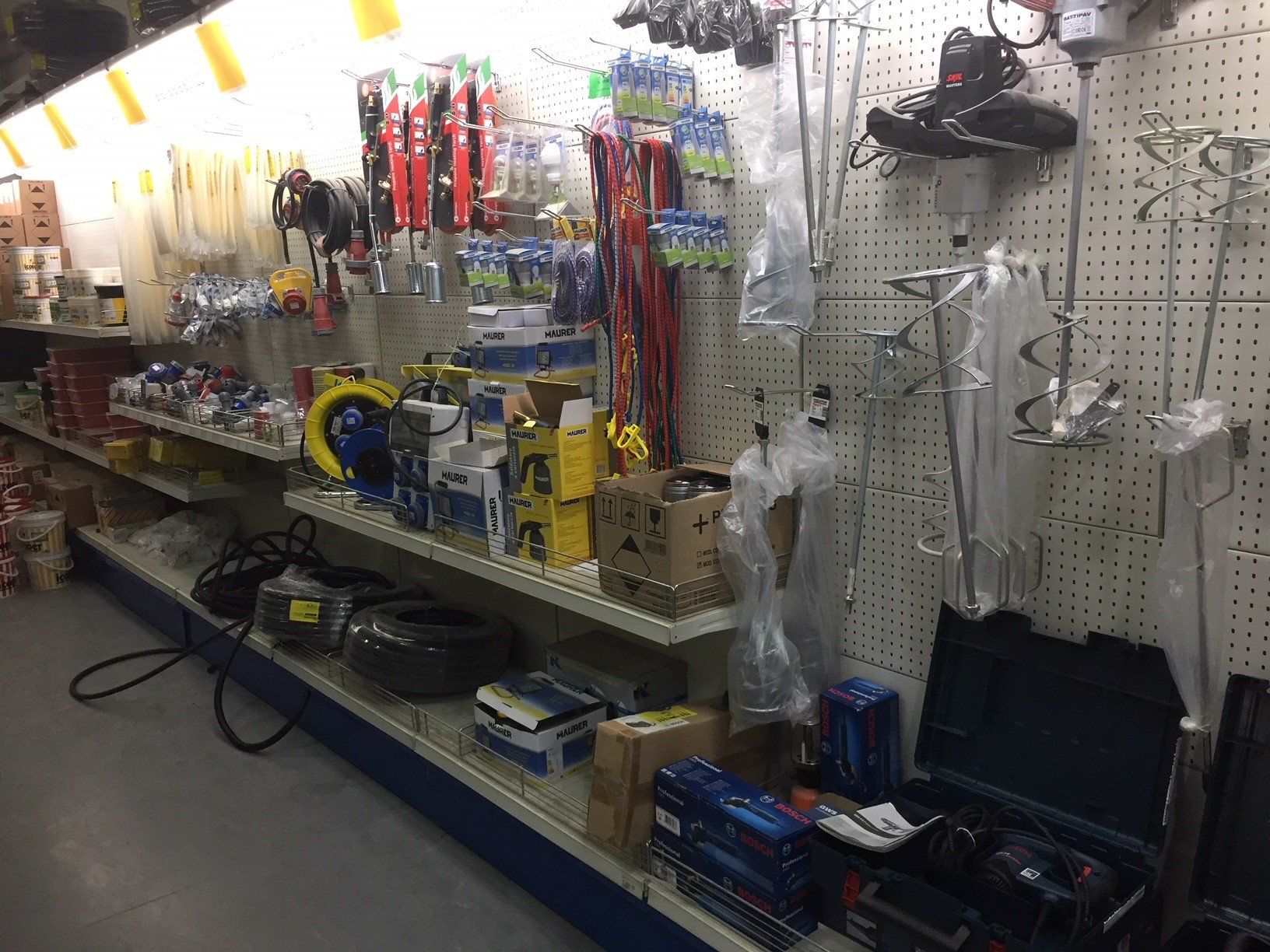 Corsia di un negozio di ferramenta piena di attrezzi e attrezzature su scaffali di metallo.