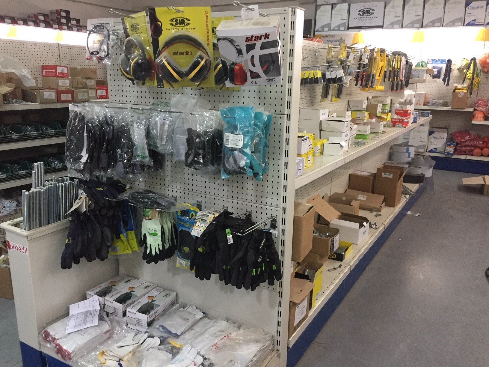 Scaffali di un negozio di ferramenta pieni di attrezzi, guanti e articoli confezionati.