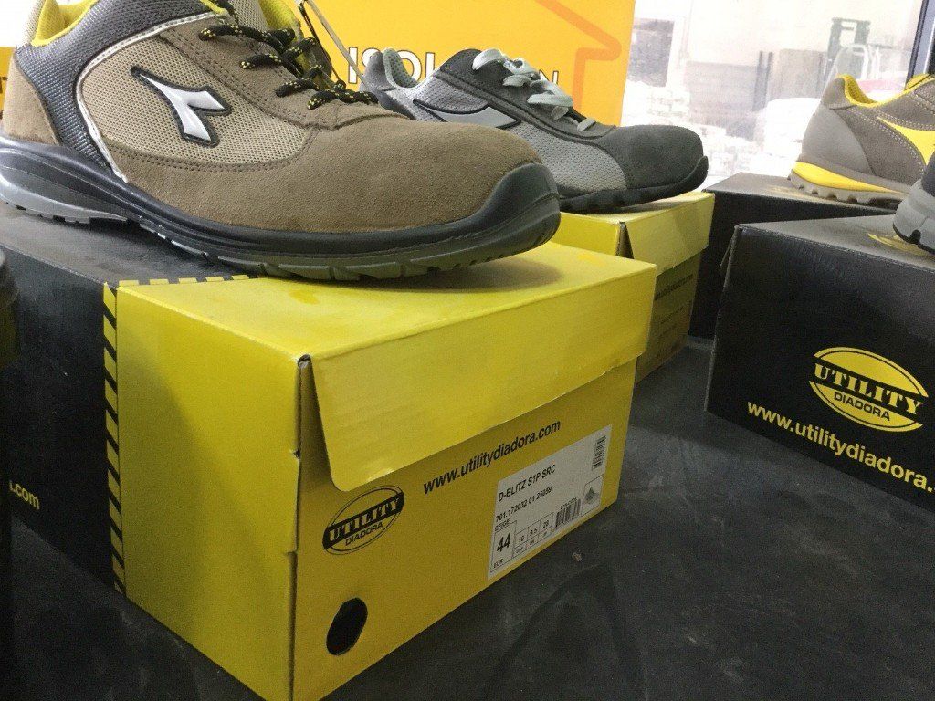 Scarpe antinfortunistiche esposte in scatole gialle, al chiuso.