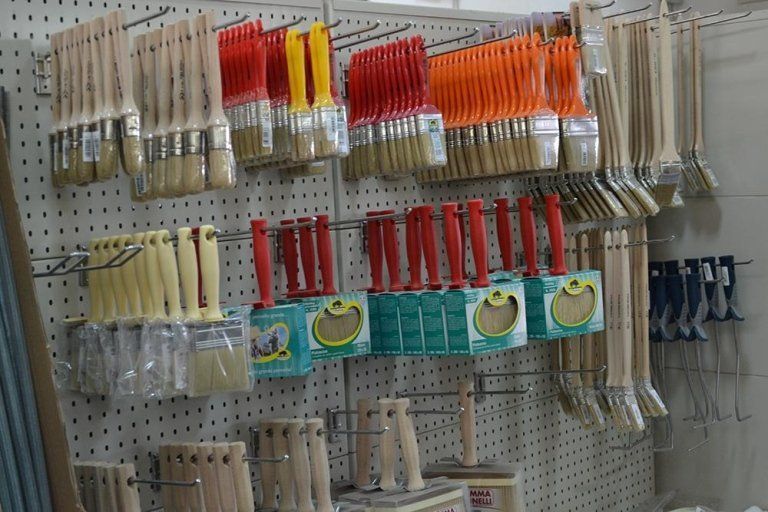 Pennelli appesi a un pannello forato, di vari colori e misure.