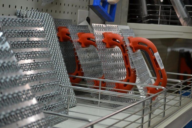 Attrezzi da costruzione in metallo con manici arancioni esposti sullo scaffale di un negozio.