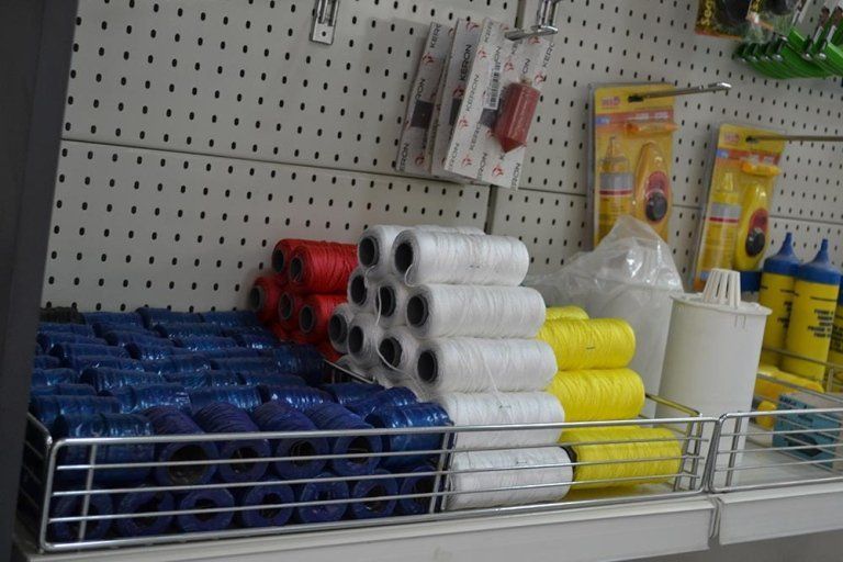 Scaffali pieni di rocchetti di spago di vari colori, tra cui blu, bianco, rosso e giallo.