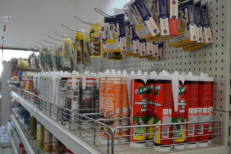 Scaffali pieni di tubetti di sigillante per l'edilizia e utensili confezionati in un negozio.