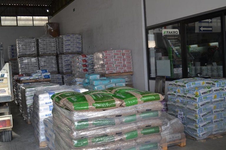 Interno di un magazzino con pile di prodotti insacchettati su pallet, avvolti nella plastica.