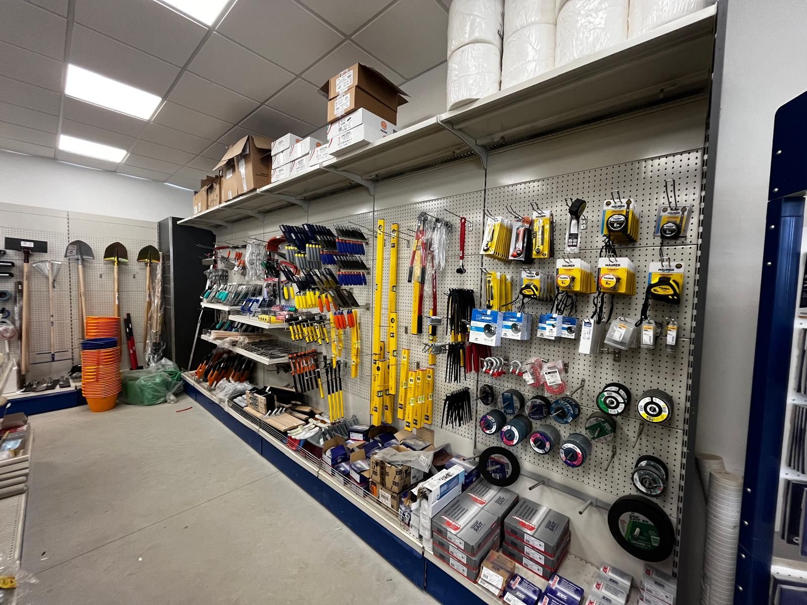 Pile di mattoni rossi e beige su pallet in un parcheggio, con un furgone per le consegne sullo sfondo.