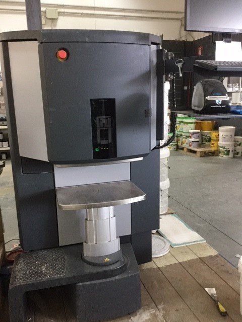 Miscelatore per vernici in un negozio, grigio scuro e argento, con pannello di controllo e piano di lavoro.