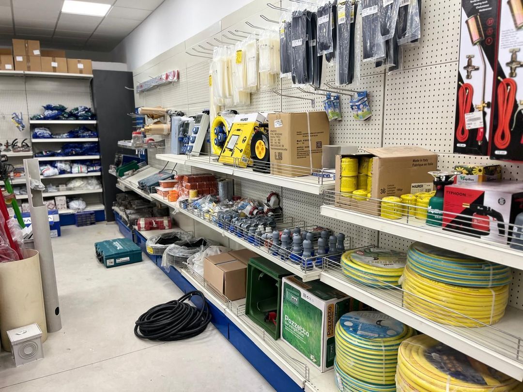 Scaffali pieni di attrezzi e attrezzature in un negozio di ferramenta. Scaffali bianchi contro pareti bianche, finiture blu.
