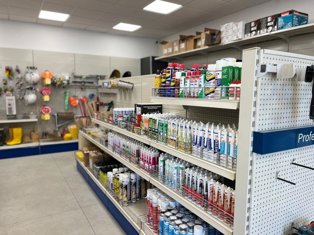 Interno di un negozio di ferramenta con scaffali che espongono attrezzi, calafataggi e forniture.