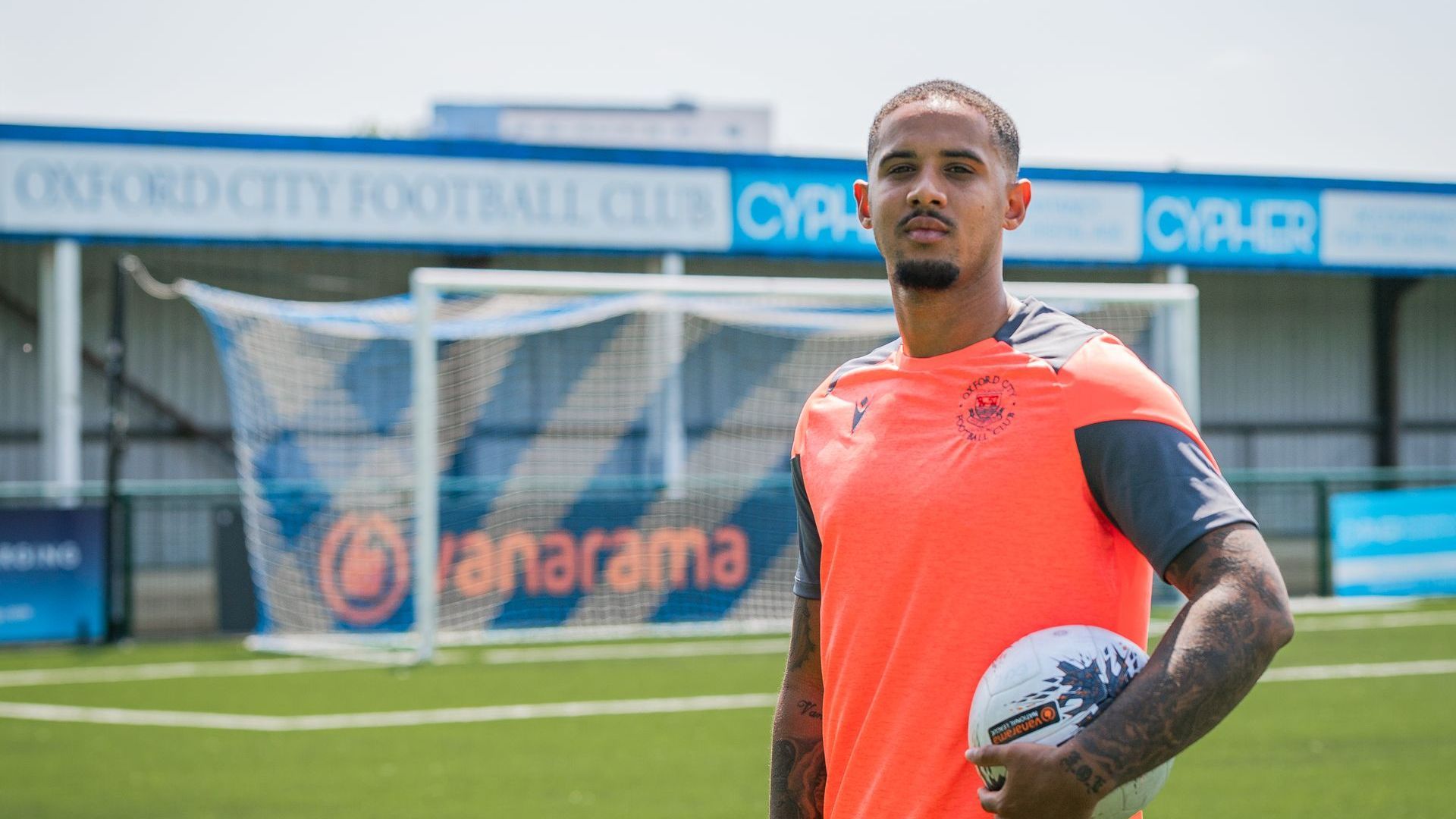 Cole Kpekawa holds football next to Oxford City FC sign
