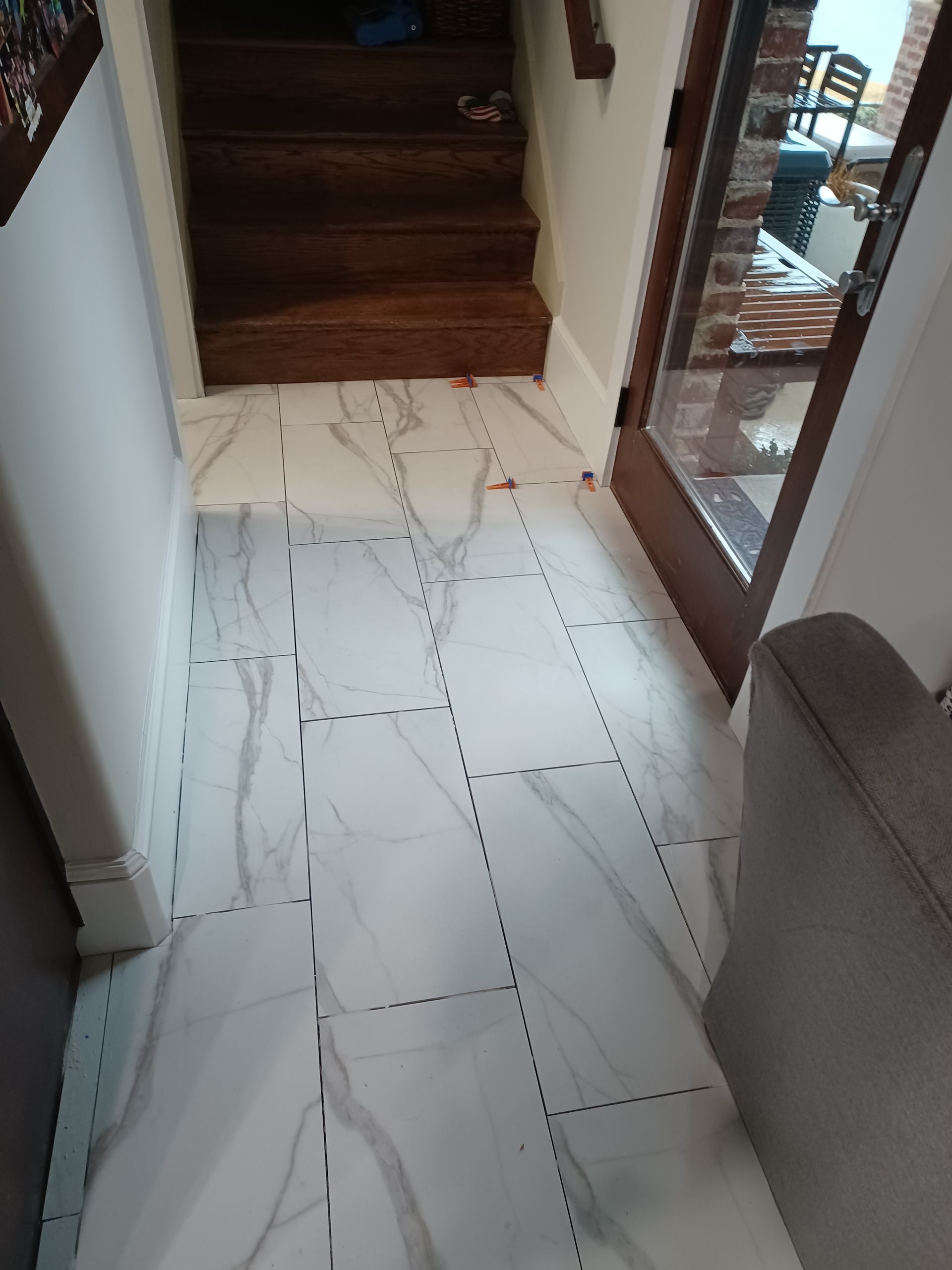 A hallway with a marble floor and stairs in the background