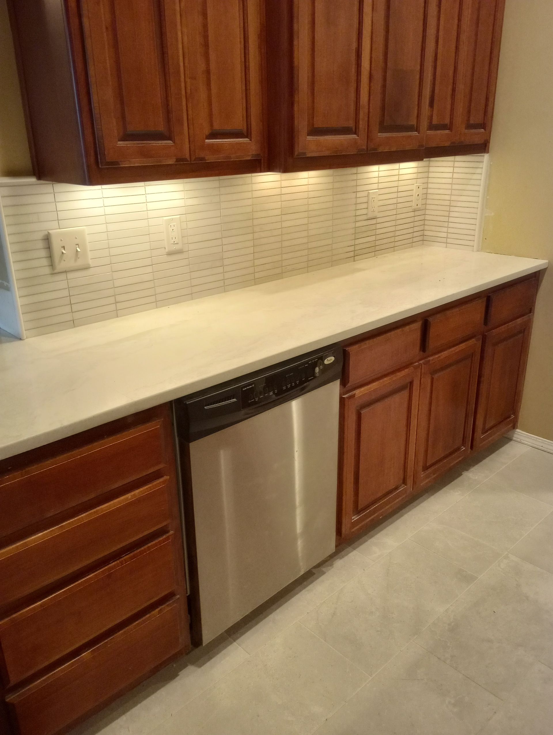 A kitchen with wooden cabinets and a stainless steel dishwasher.
