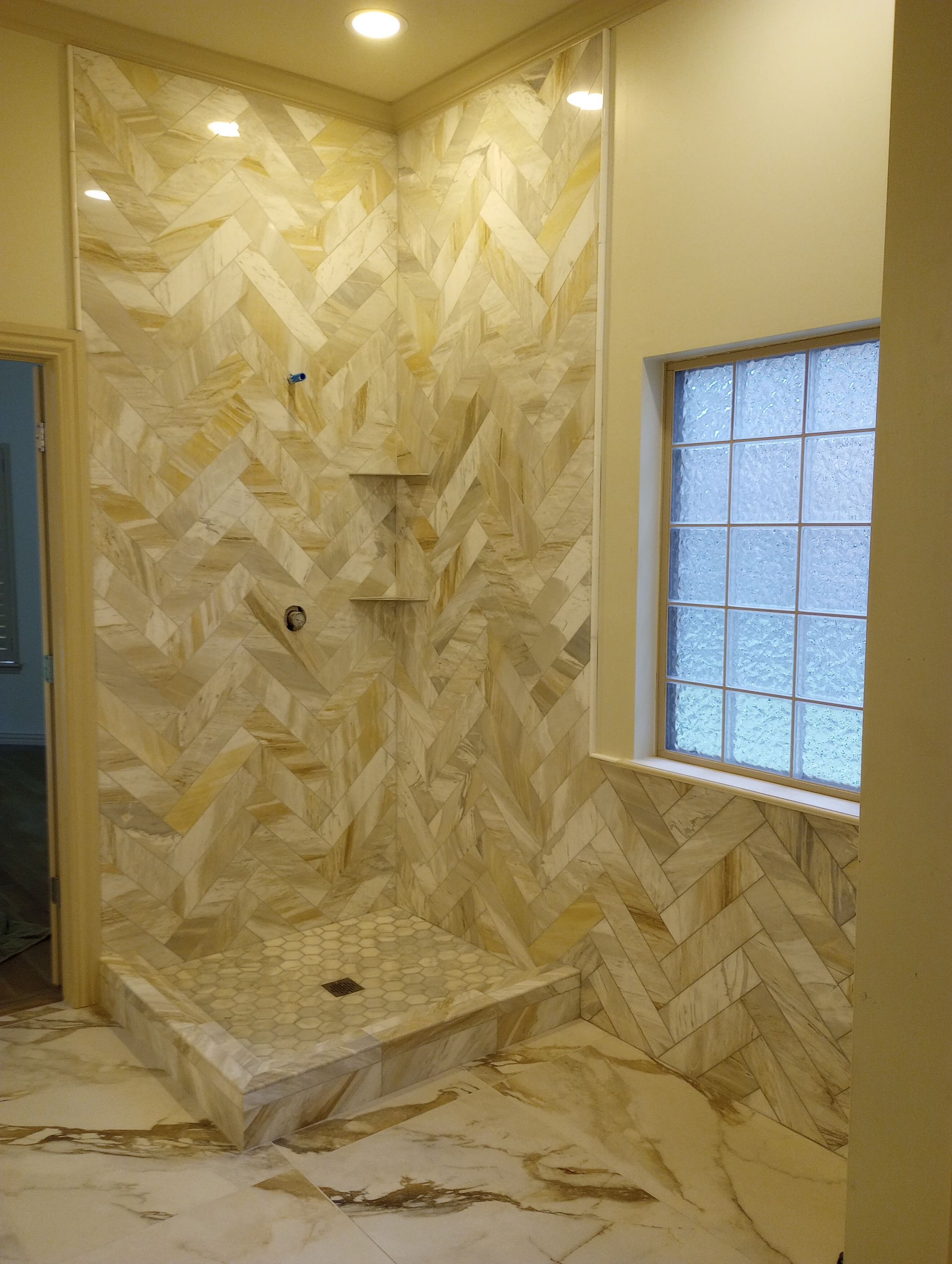 A bathroom with a walk in shower and a window.