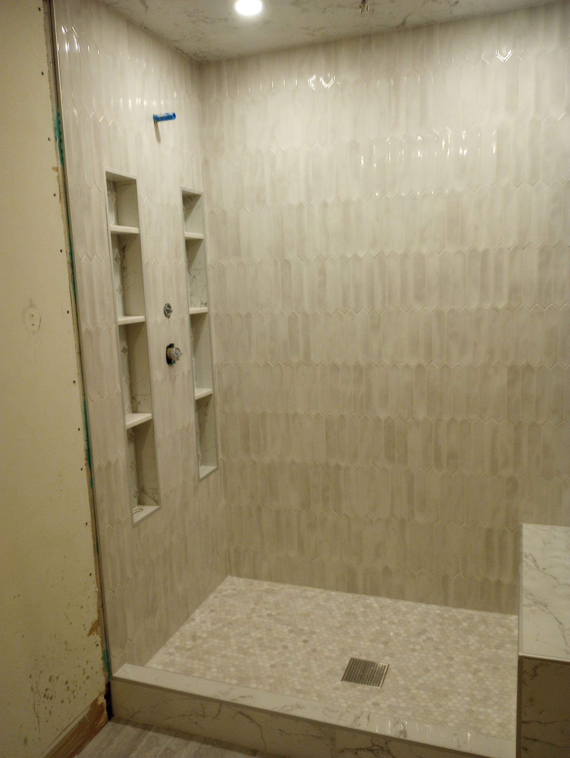 A bathroom with a walk in shower and shelves.