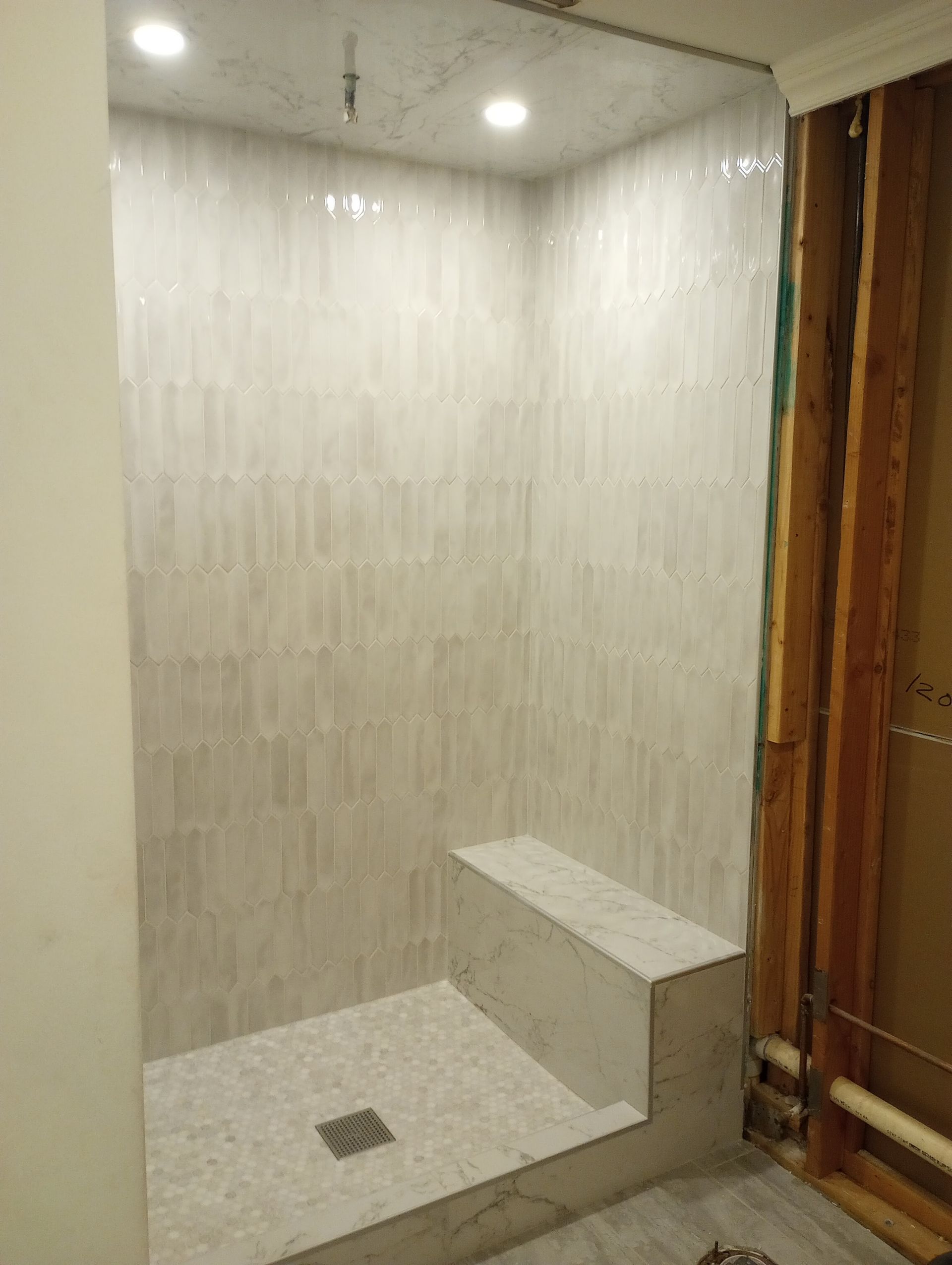 A bathroom with a walk in shower and a bench.