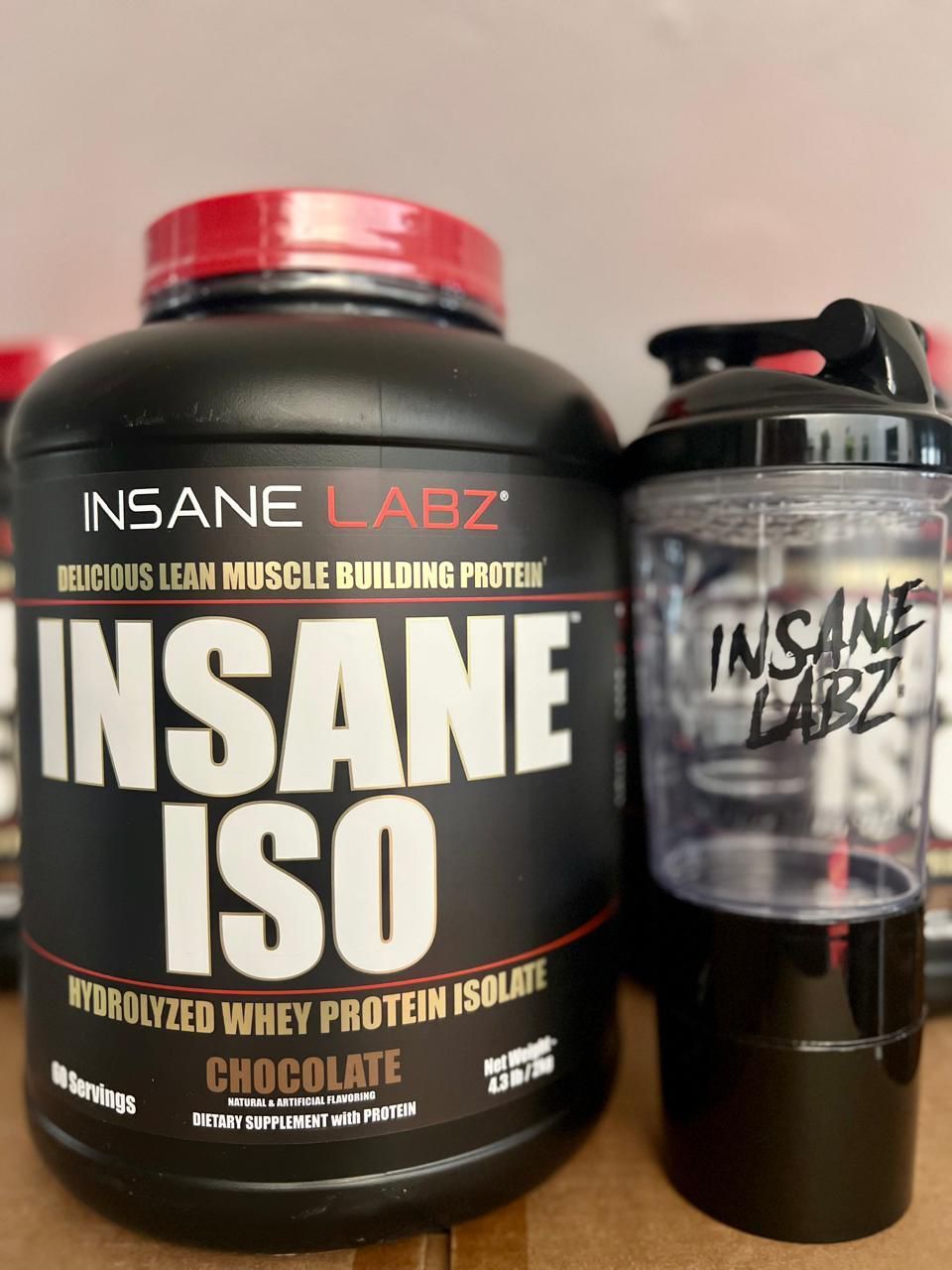 Envase de proteína de suero de leche con sabor a chocolate de Insane Labz con botella mezcladora a juego.