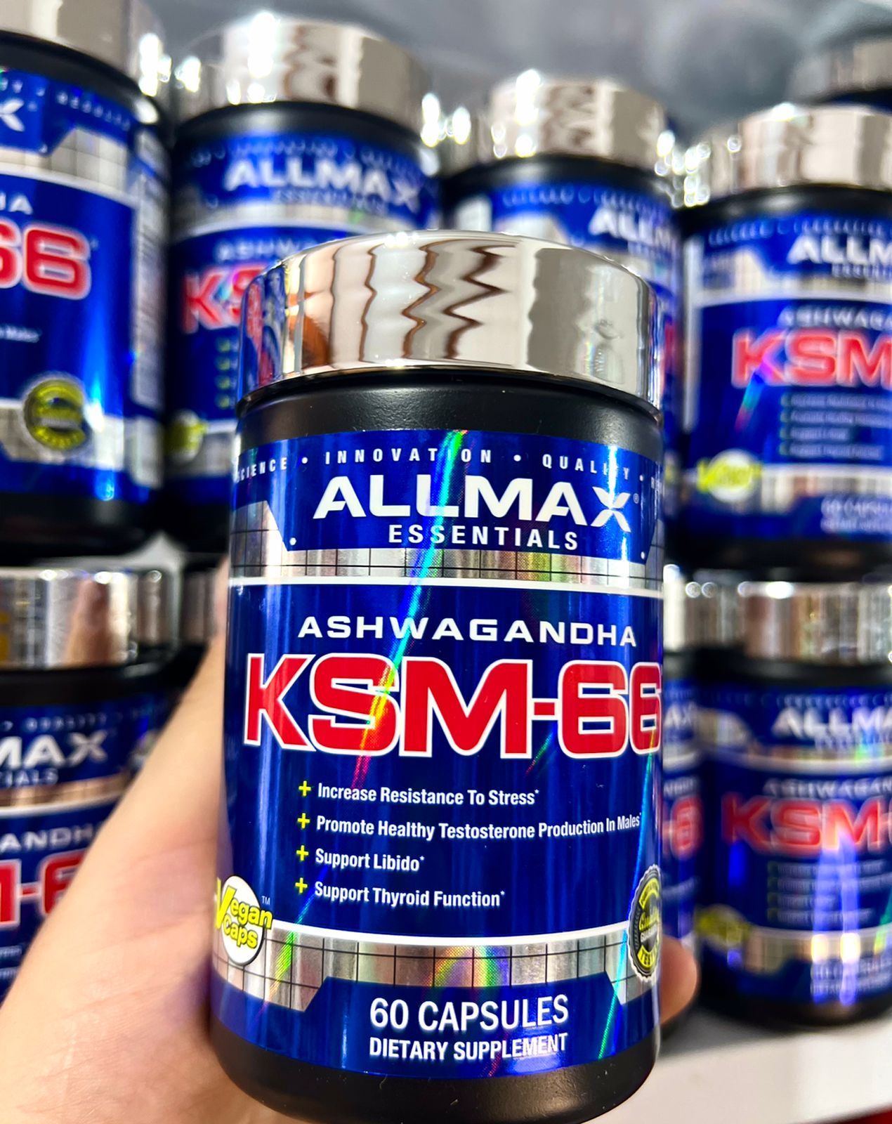 Frasco del suplemento de ashwagandha Allmax Essentials KSM-66 frente a frascos a juego.