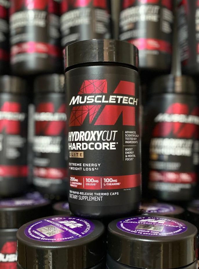 Botellas del suplemento MuscleTech Hydroxycut Hardcore Elite, negras con detalles rojos, apiladas en un expositor.