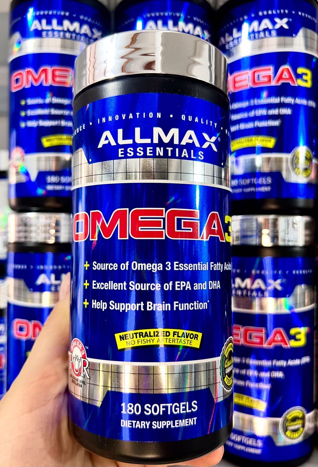 Frasco de suplemento Allmax Omega-3 con etiqueta azul, rodeado de varios frascos iguales.