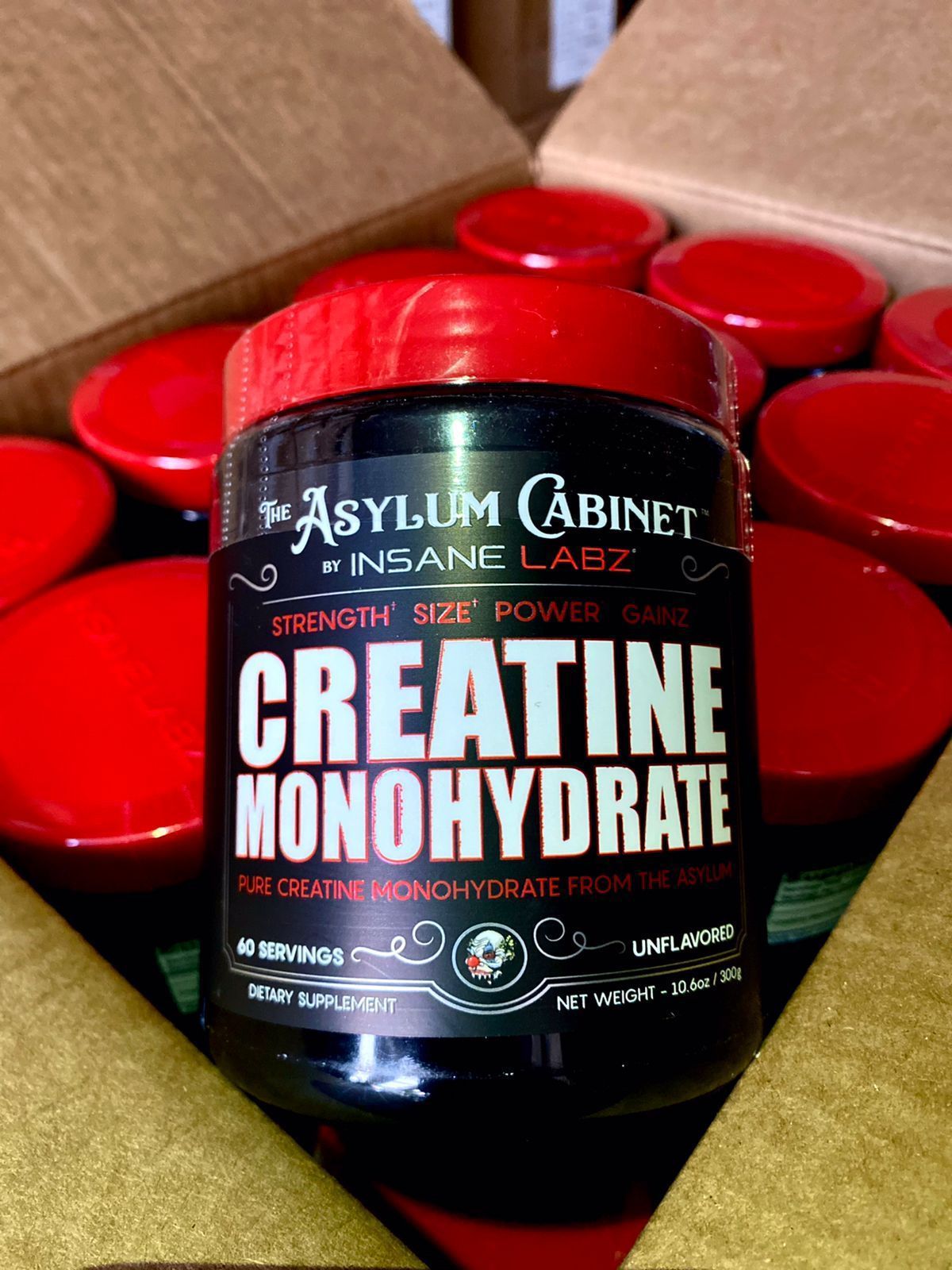 Frasco de suplemento de monohidrato de creatina con tapa roja en una caja abierta.