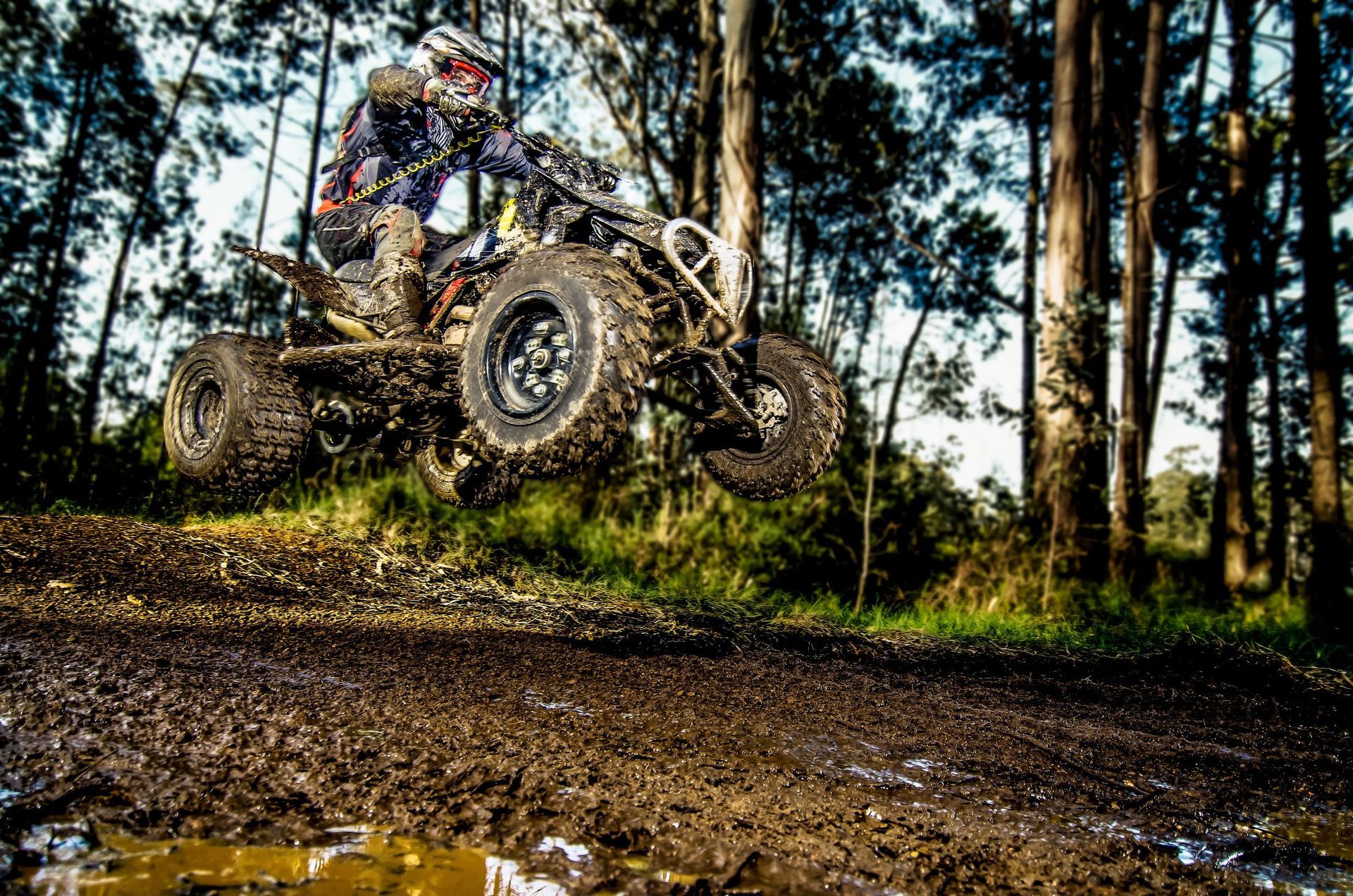 quad rider jumping on muddy forest