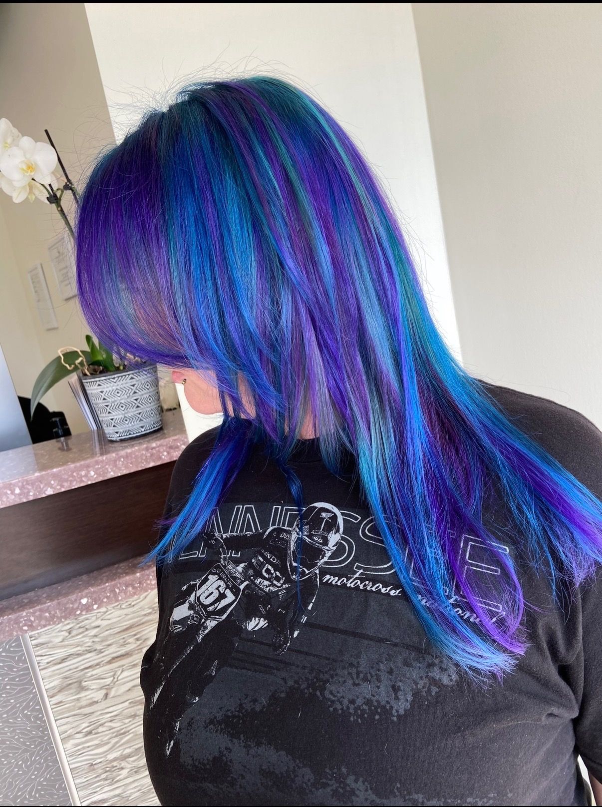 Woman with long, vibrant blue and purple hair; wearing a black t-shirt.
