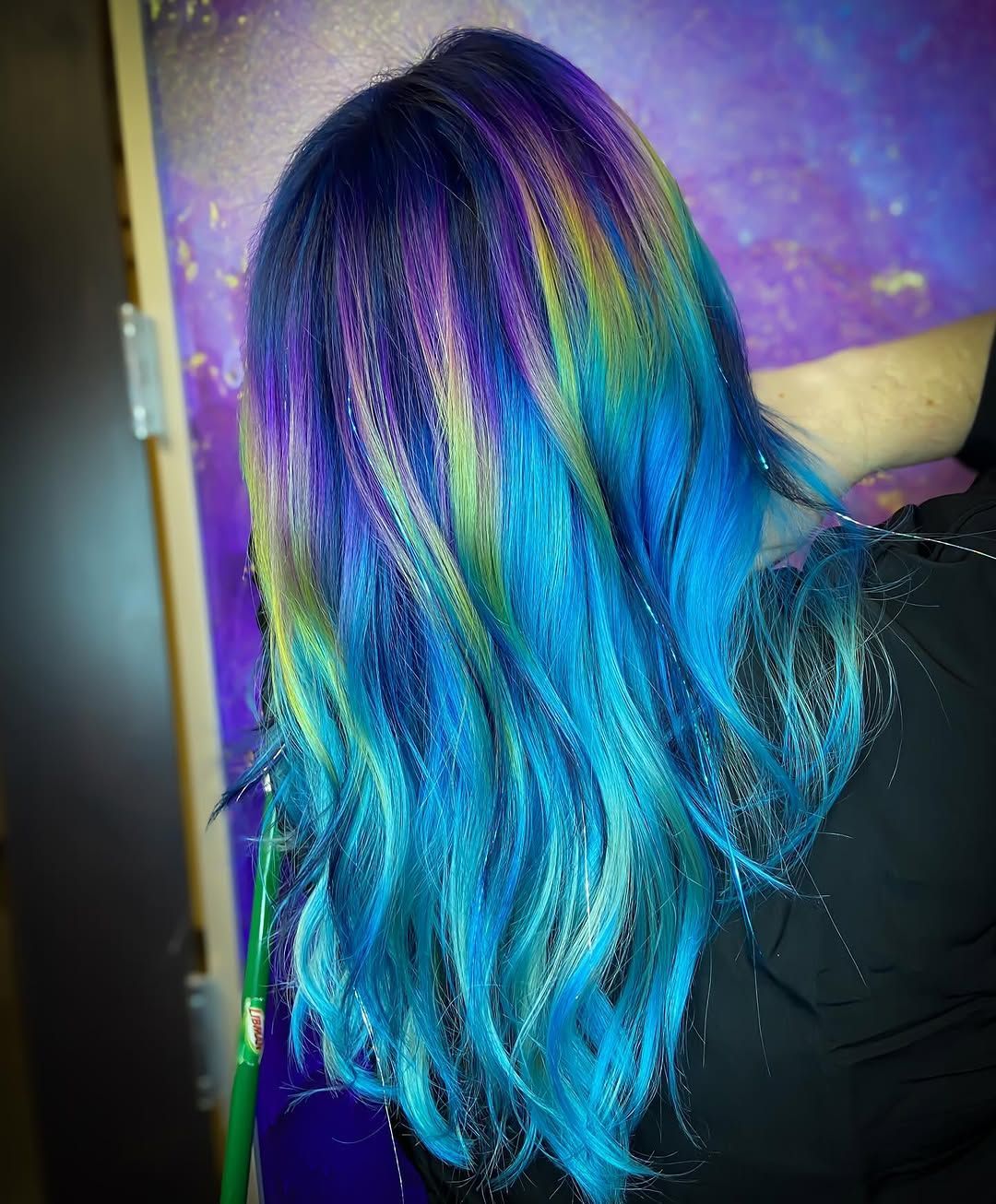 Woman's long hair dyed in iridescent shades of blue, purple, and green.