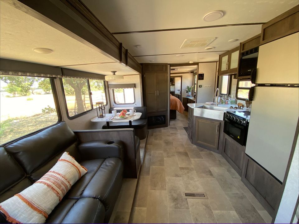 Interior view of a modern RV featuring a dining area, kitchen, and a cozy seating arrangement.