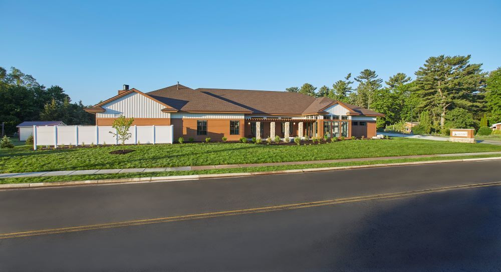 A large house with a brown roof is sitting on the side of a road.