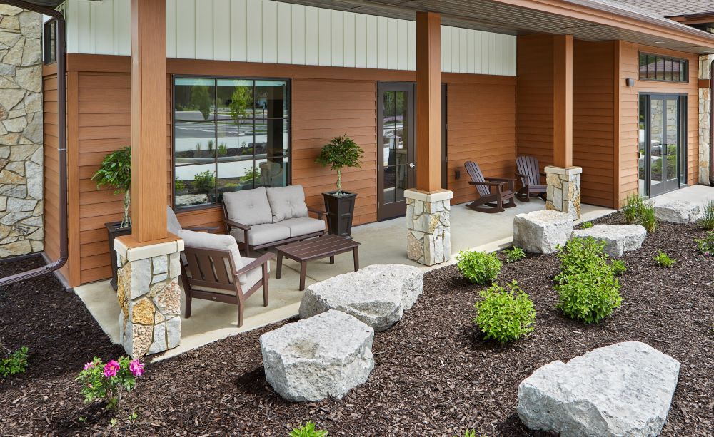 A patio with a couch , chairs , and a table in front of a building.