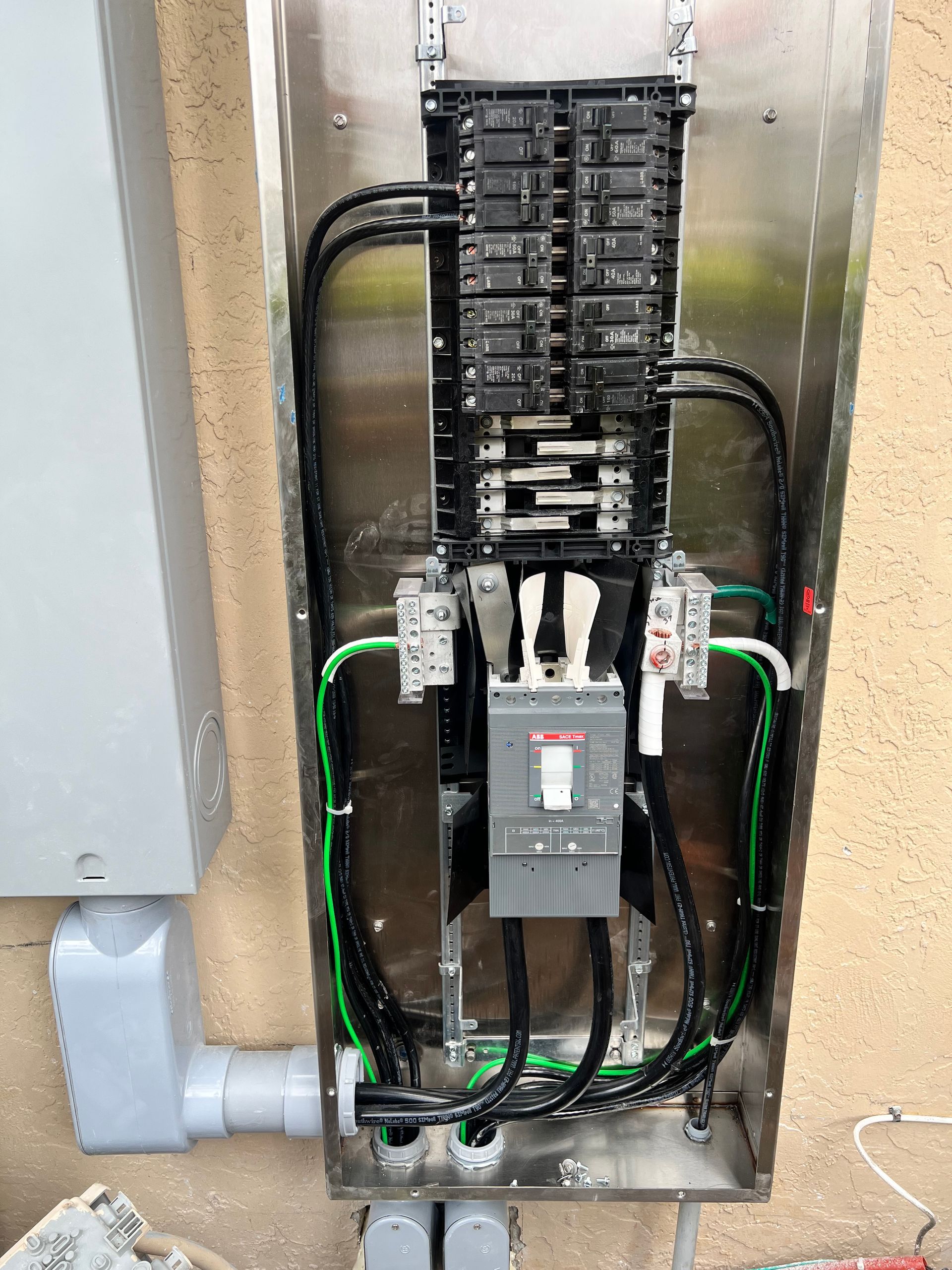 Electrical panel with black wires, green ground wires, and circuit breakers in a metal enclosure.