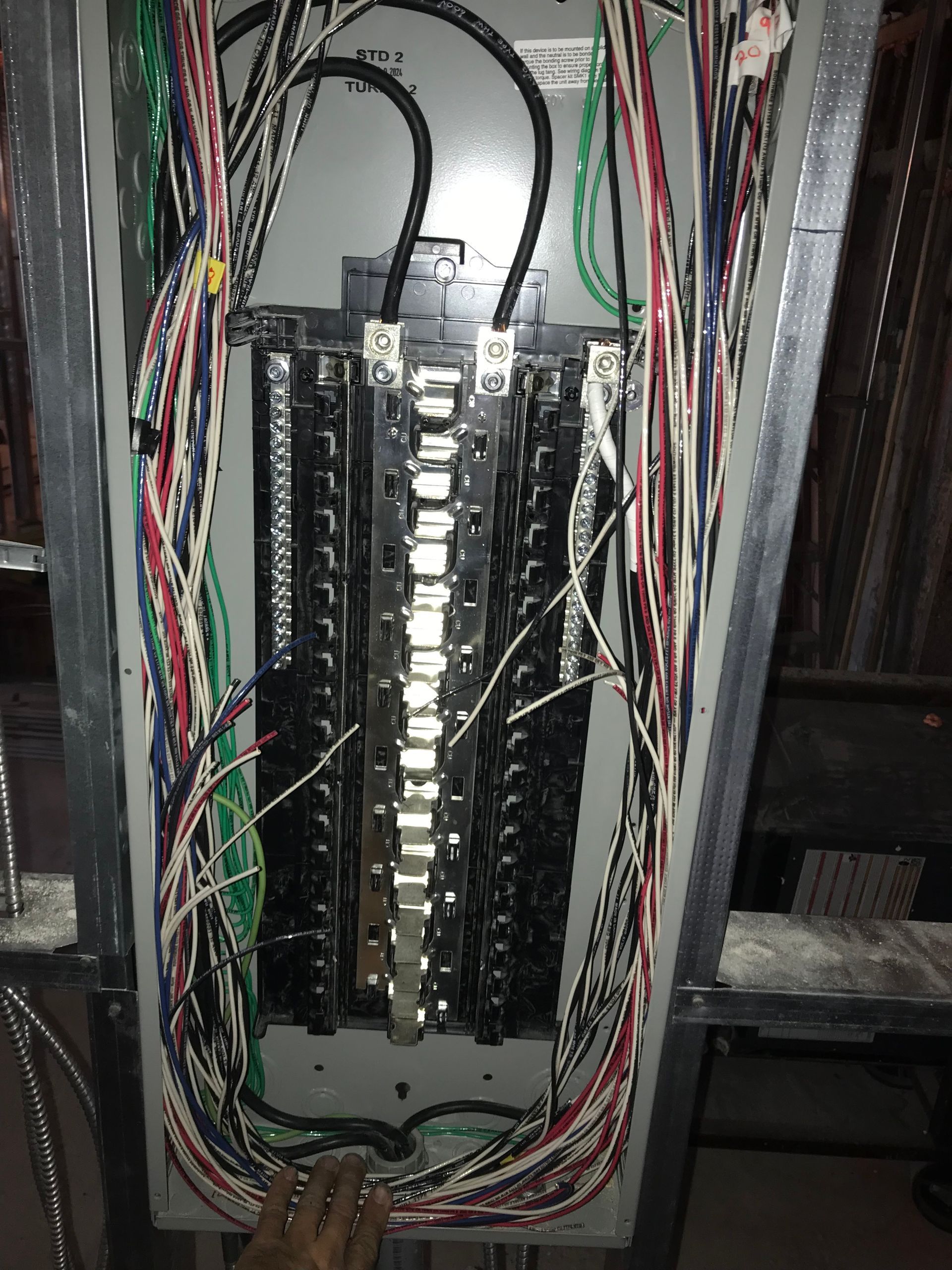 Electrical panel with numerous wires connected to circuit breakers.