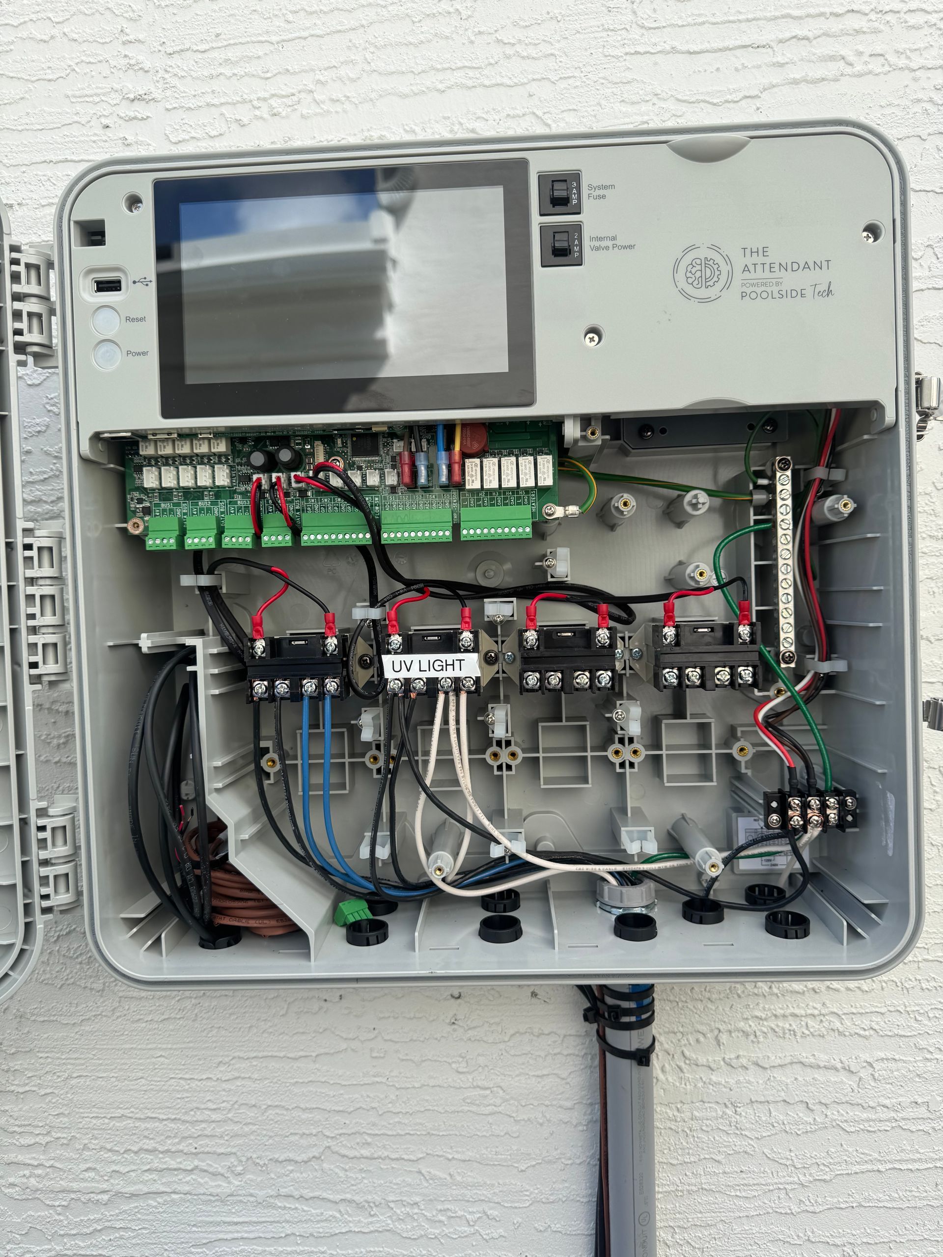 Open irrigation system control box, displaying internal wiring, circuit boards, and a screen.
