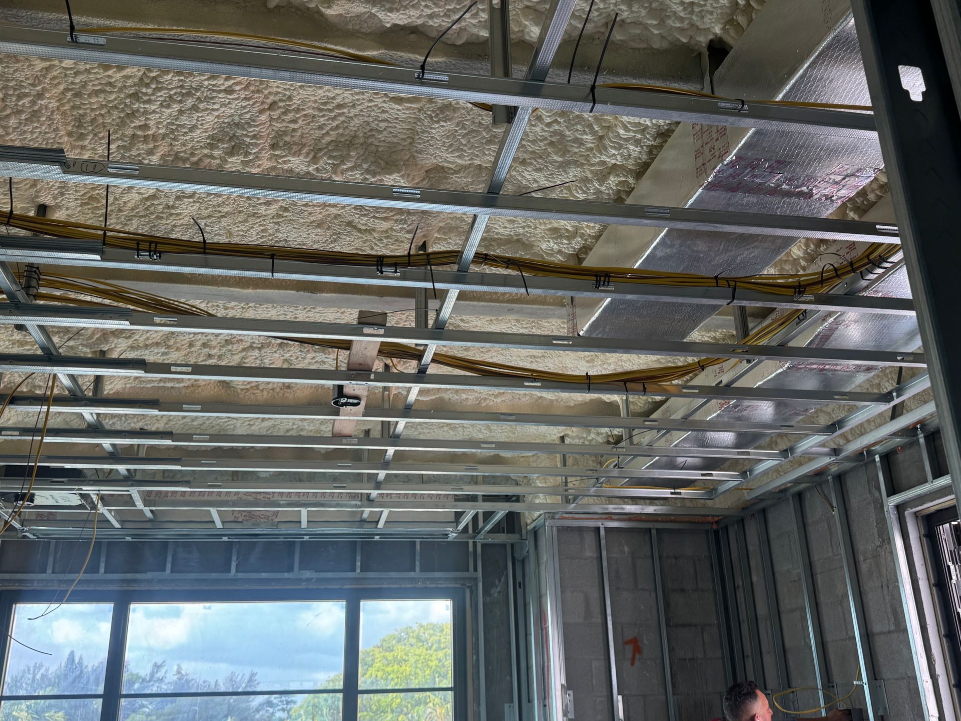 Construction site ceiling framework with electrical wiring and insulation.