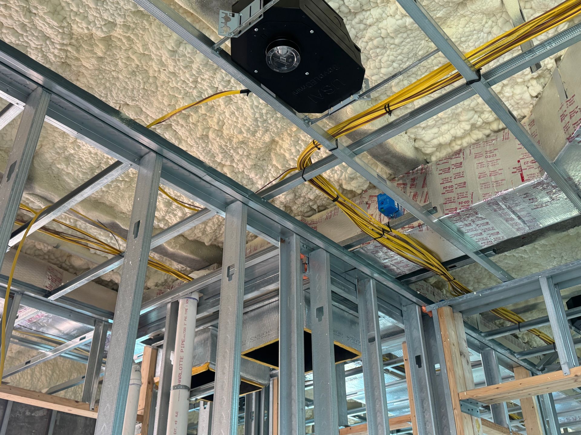 Interior construction view of metal framing, wiring, and spray foam insulation.