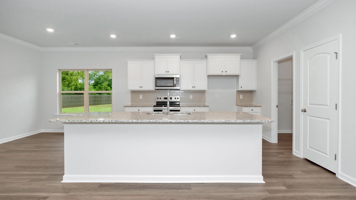Modern kitchen with white cabinets, granite countertop island, and hardwood floors.