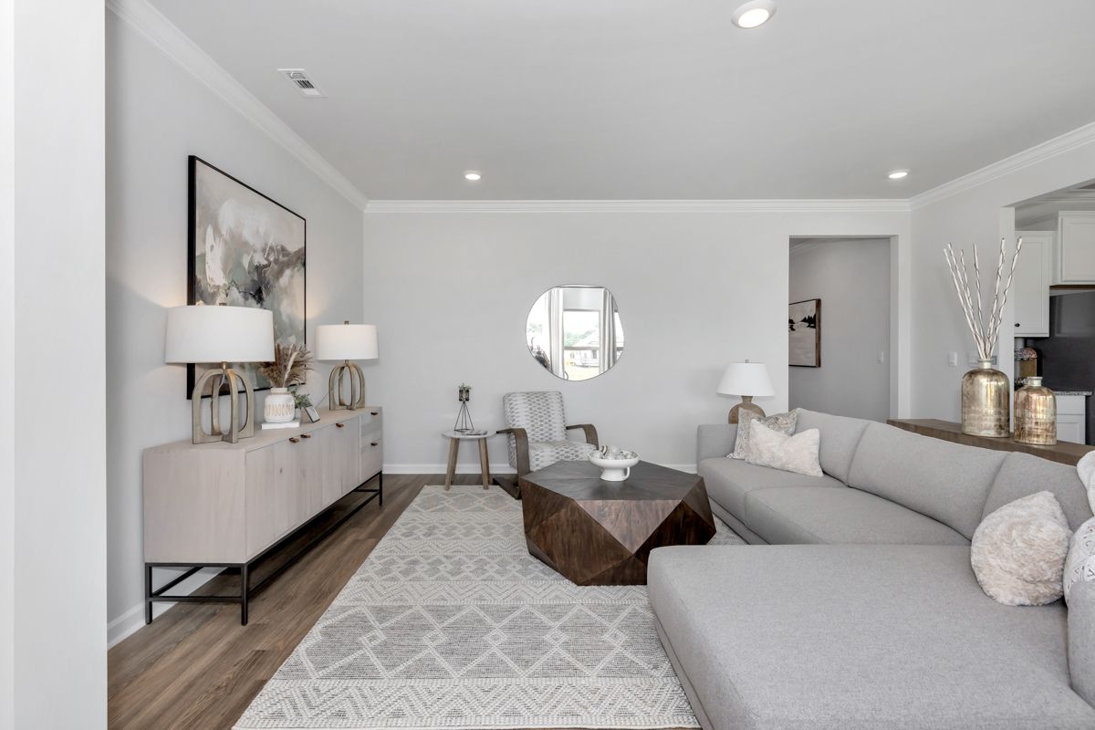Spacious living room with grey sectional sofa, light wood console, and geometric rug.