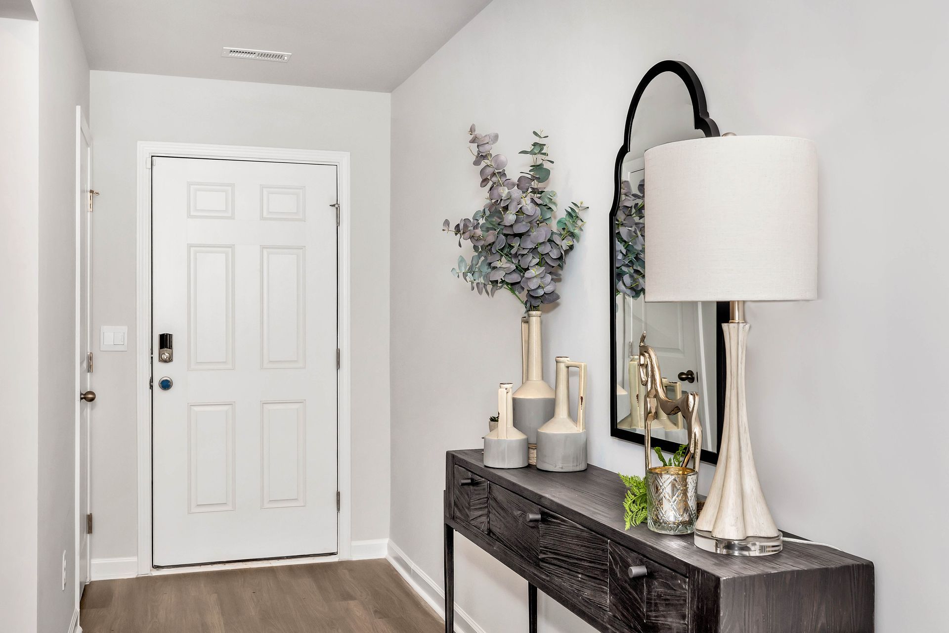 Entryway with a console table, mirror, lamp, and front door.