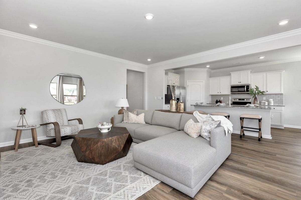 Living room with gray sofa, wooden coffee table, and open kitchen in the background.