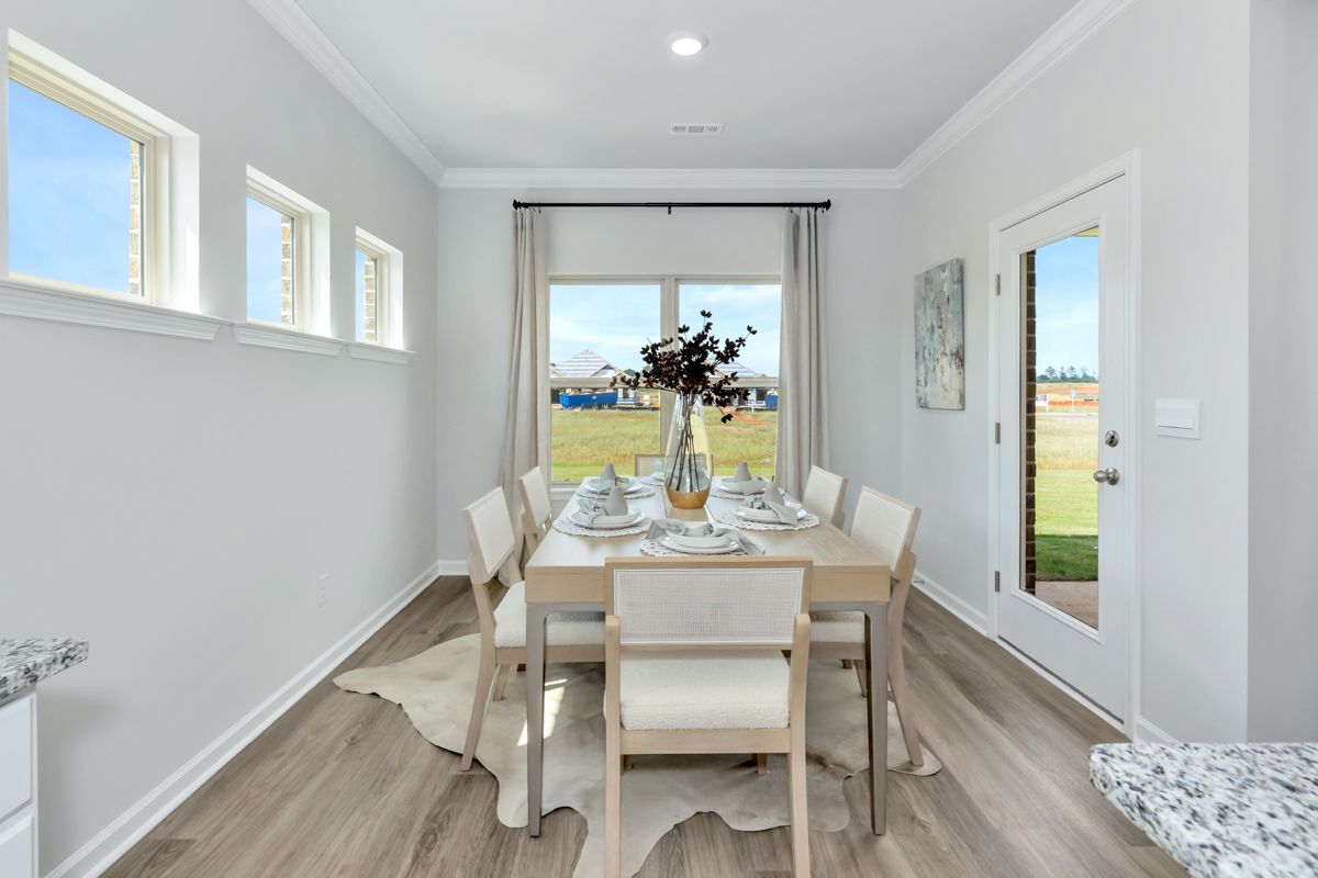 Dining room with table set for six, windows, and white walls.