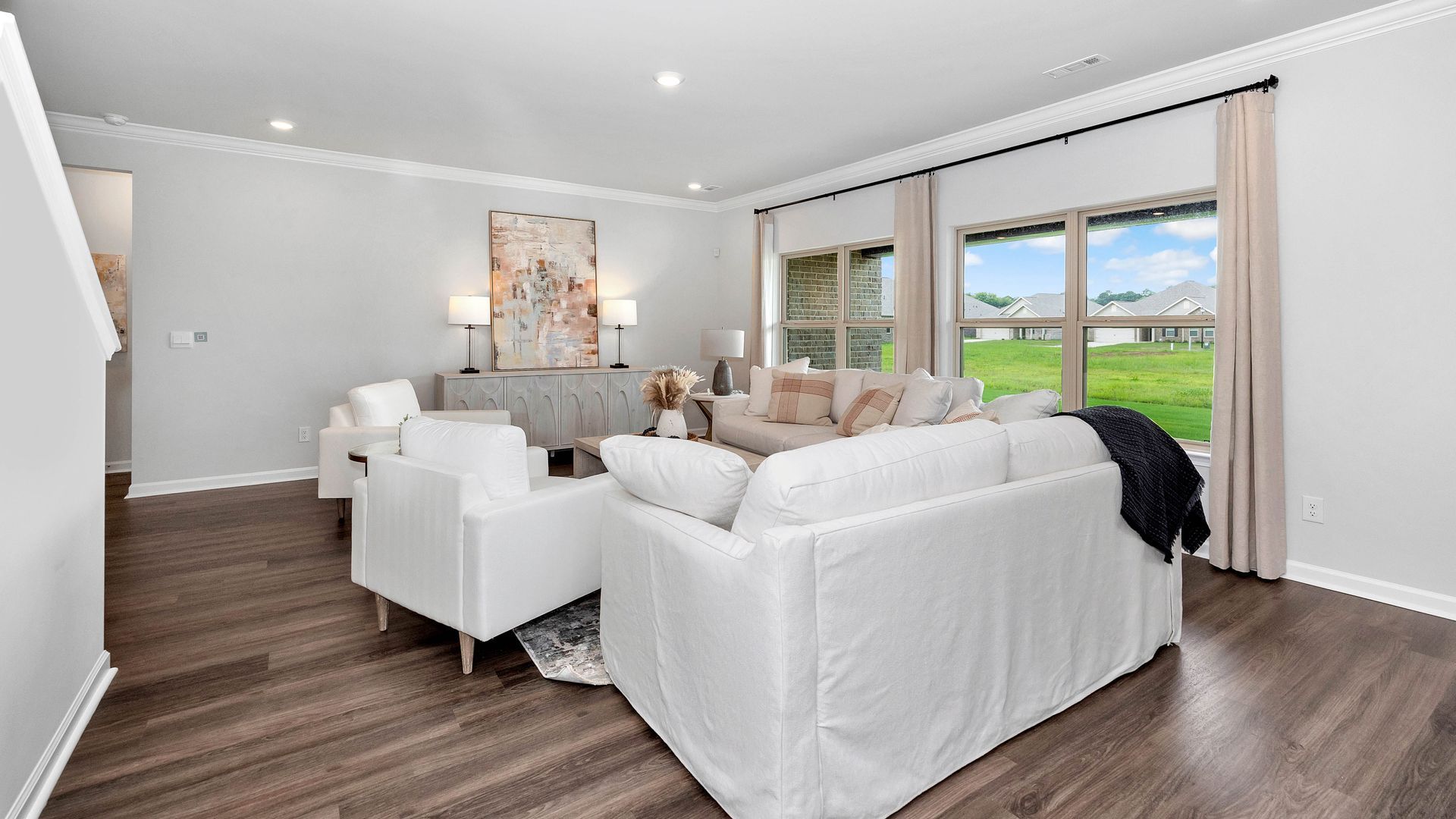 Living room with white sofas, large windows, and hardwood floors.