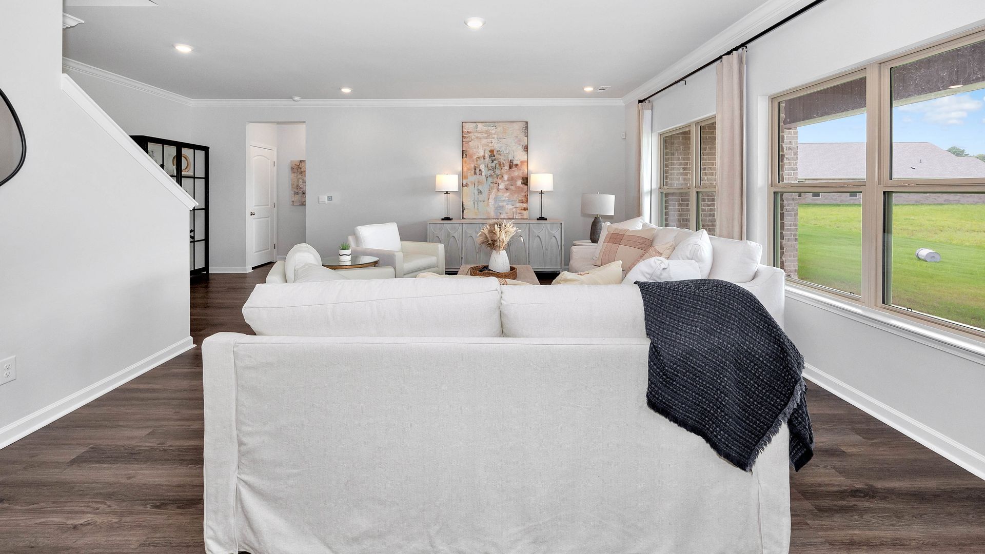 Living room with white sofa, windows, and artwork.