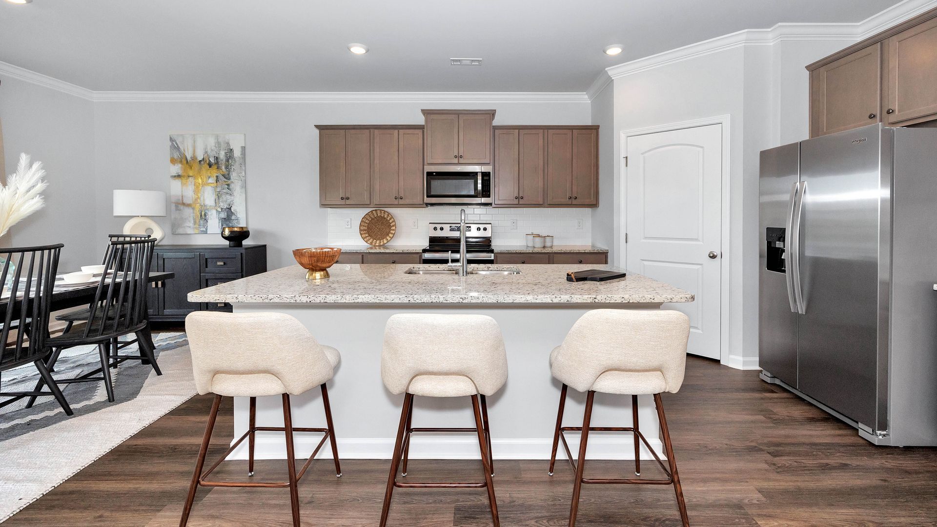 Kitchen with island seating, stainless steel appliances, and brown cabinetry.