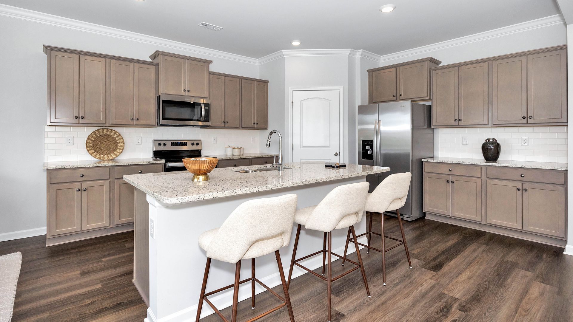 Modern kitchen with wood cabinets, island with bar stools, and stainless steel appliances.