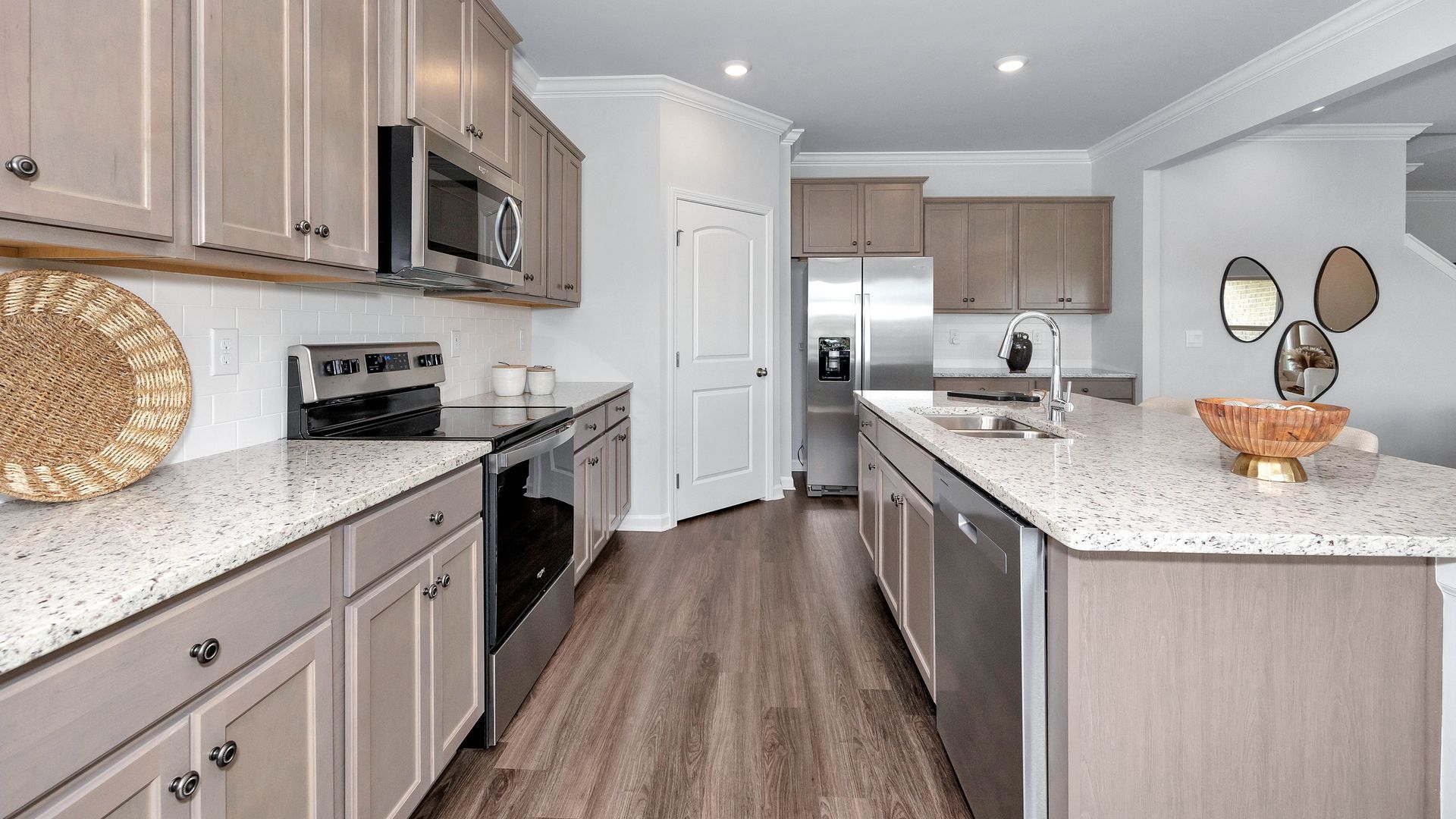 Modern kitchen with light gray cabinets, speckled countertops, stainless steel appliances, and wood-look flooring.