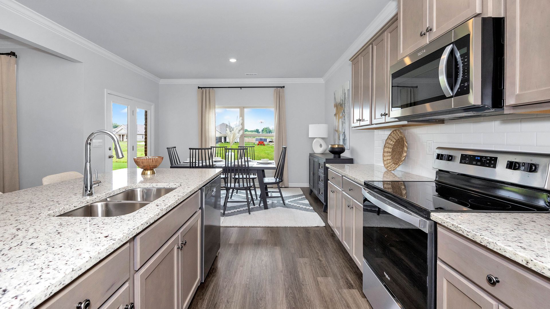 A modern kitchen with granite countertops, stainless steel appliances, and a dining area with a window.