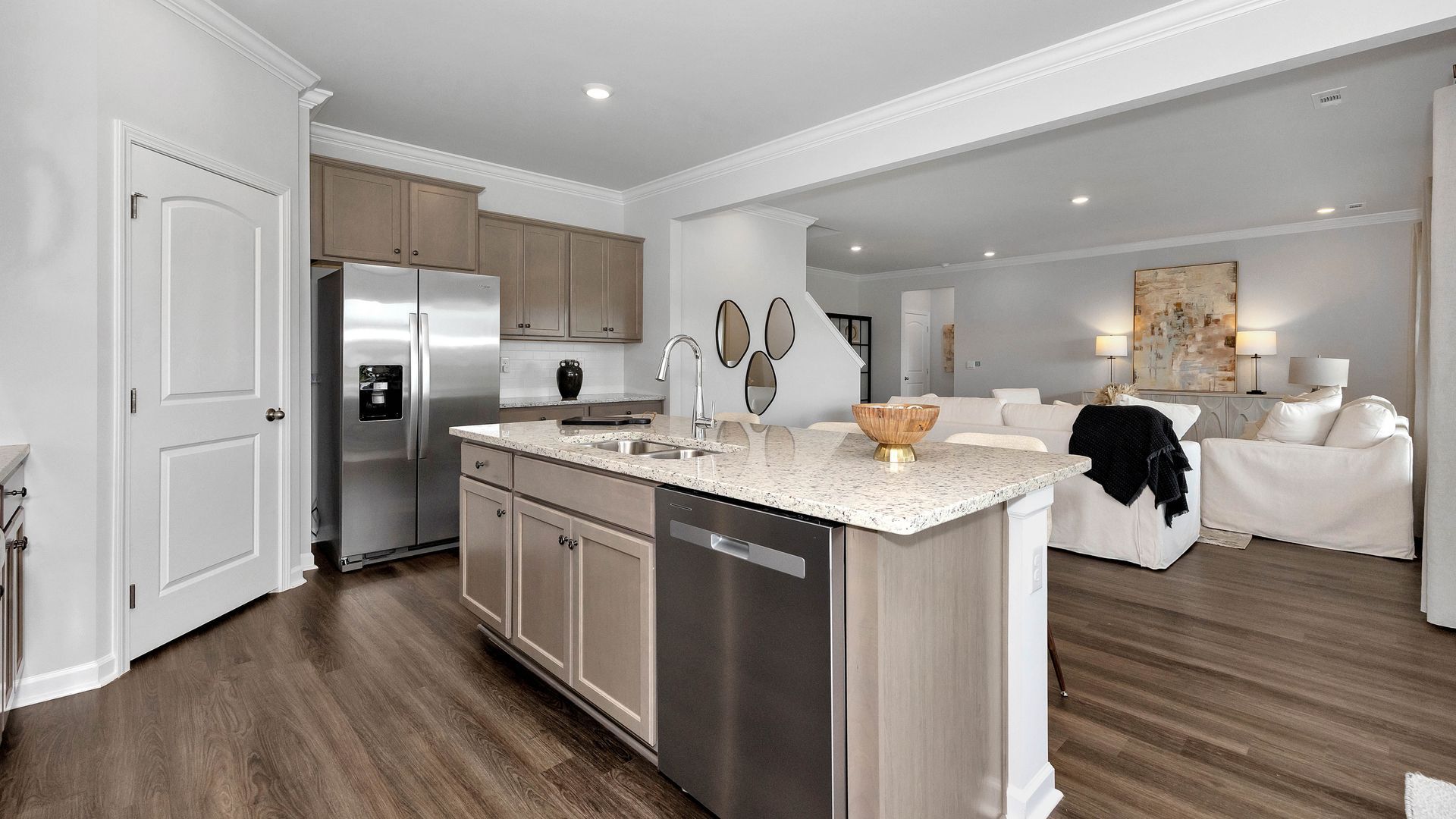 Modern kitchen with stainless steel appliances, island, and open view to the living room.